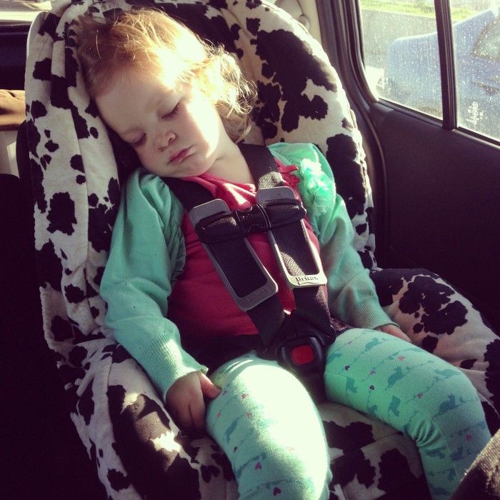 A young girl asleep in a child's car seat